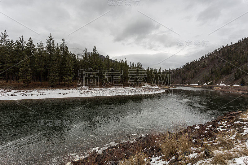 美丽的风景，平静的河流流经树木和岩石覆盖的山谷与雾和雪