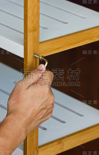 亚洲人的手用六角扳手拧紧木架。