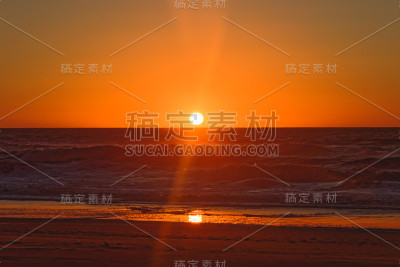 抽象的景观。海上鲜红的落日。空旷的海滩，可见的阳光，戏剧性的大海