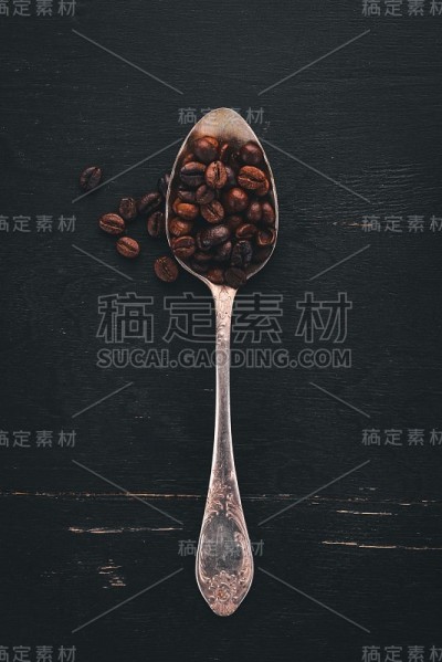 咖啡豆。在一个木制的背景上躺在勺子上。前视图。副本的空间。