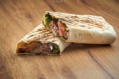 开胃的多纳卷与蔬菜，酱汁和小牛肉皮塔饼，服务在木制背景。传统街头小吃——沙瓦玛
