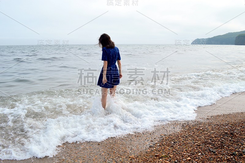 在阴天下雨前，忧郁周到的女人穿着蓝色衣服去海边。她往水里看