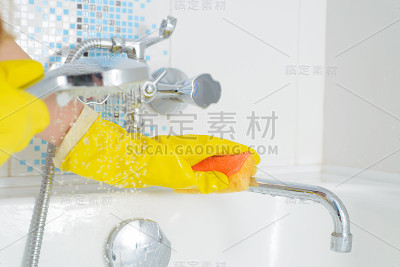 清洁-清洁浴室的水槽和水龙头与黄色橡胶手套与橙色海绵-家务，春季清洁概念