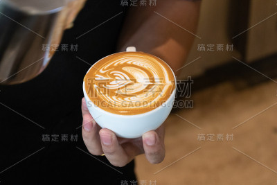 咖啡师专注于牛奶和咖啡的拉花艺术。专业的咖啡师将蒸牛奶倒入咖啡杯，制作美丽的拉花艺术。