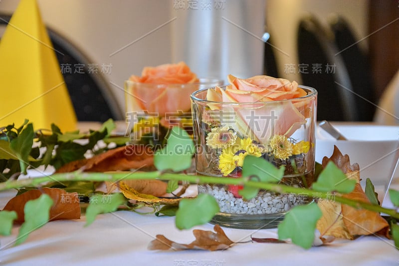 餐桌装饰用秋叶和鲜花装在玻璃杯里