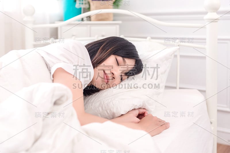 肖像美丽的亚洲年轻女子睡在床上枕着舒适和快乐的休闲，女孩以放松为健康和生活方式的理念。