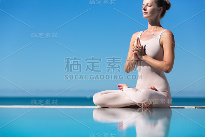在泳池边做瑜伽的女人。