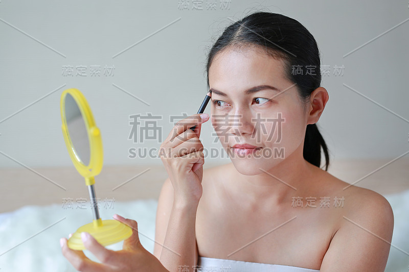 漂亮的女人用眉笔画眉毛。美丽的概念。