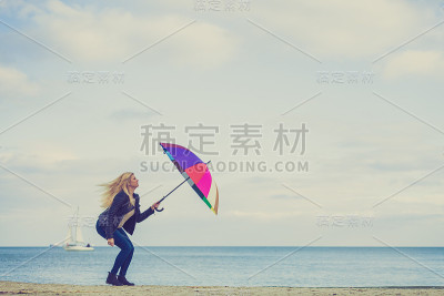 女人用五颜六色的伞在海滩上跳跃