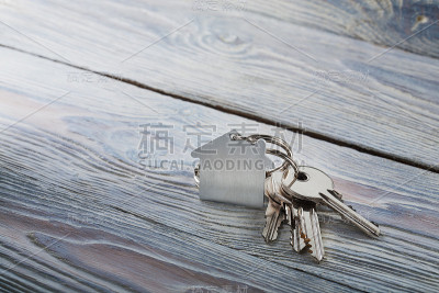 房子的钥匙与钥匙链在白色木制背景