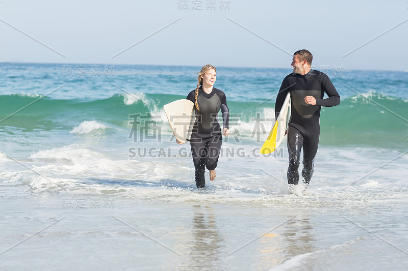 在海滩上玩冲浪板的情侣