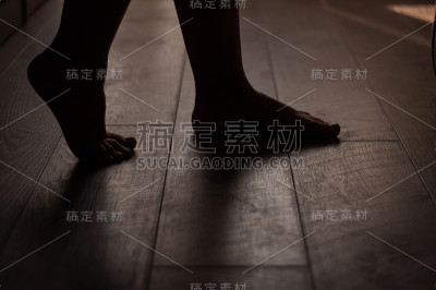 女人的腿放在温暖的木地板上