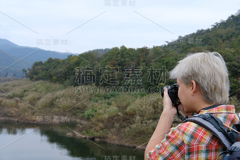 旅行者与背包旅行的人在山和湖。旅游背包客用相机拍照。生活方式，暑假概念