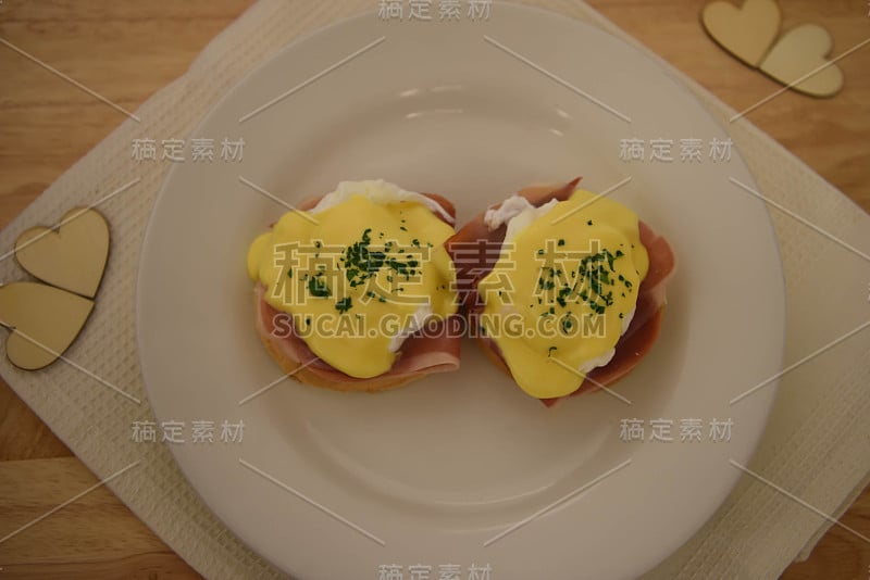 食物照片的上方视图与一个轻木厨房背景上的一个煮熟的热的传统早餐班尼迪克蛋和一个荷包蛋培根和松饼