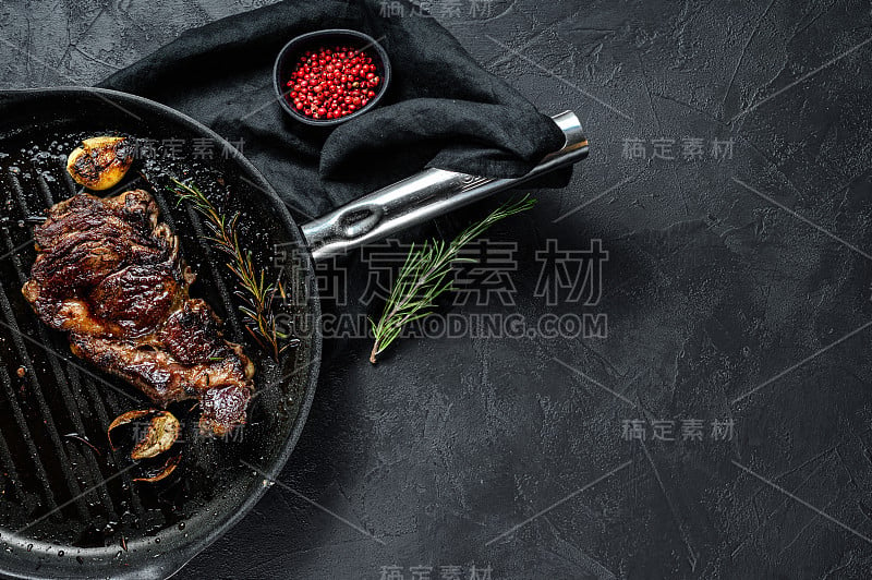 烤盘上的大理石牛排。烤的肉。有机农场的肉。黑色背景