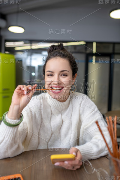 年轻女子嚼着面包棒，拿着手机