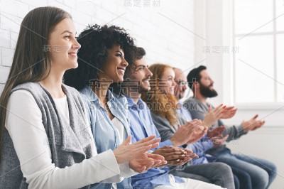 快乐的人坐在一排鼓掌来指导小组治疗