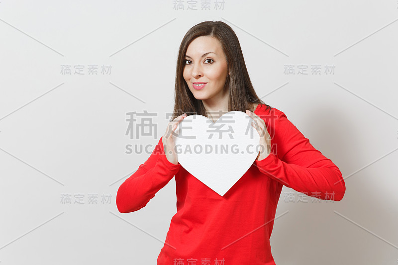 穿红衣服的漂亮女人手里拿着一颗白色的心，孤立在白色的背景上。广告版面复制。与地方的文本。情人节或国际