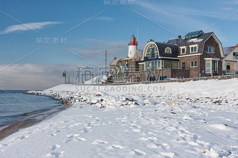 荷兰海滩上覆盖着雪和灯塔Urk的景色