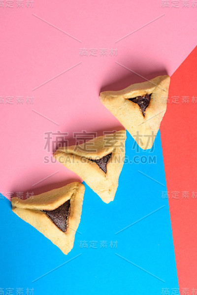 哈曼塔什填充的口袋饼干，可识别的三角形形状的犹太节日普林节在红色和蓝色的背景