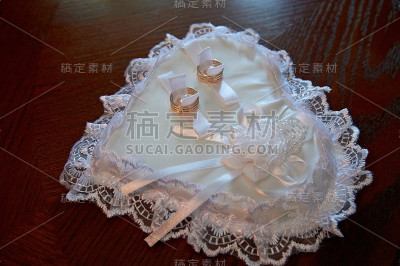 金色的结婚戒指放在白色的心型垫子上