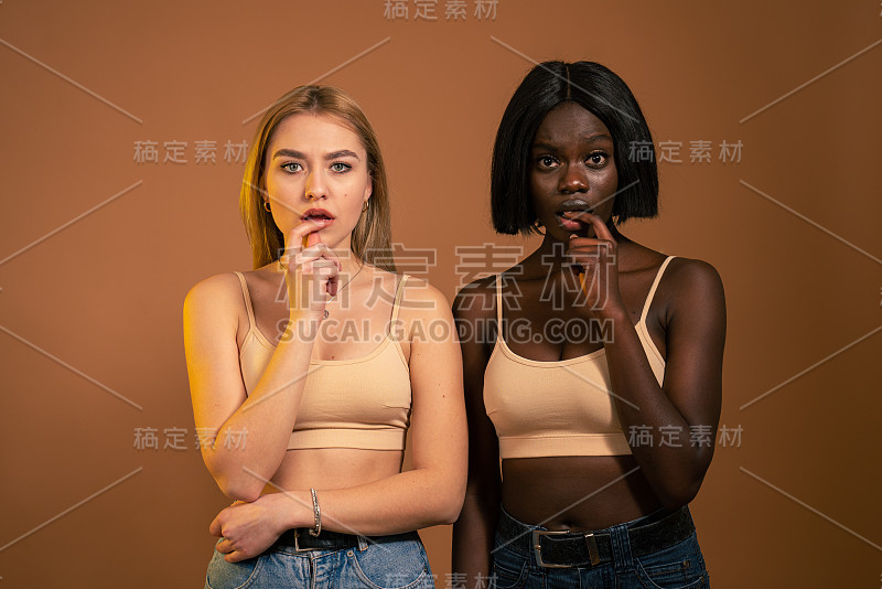 年轻漂亮的欧洲和非洲女人看起来担心，焦虑，紧张和害怕，咬指甲和看着镜头