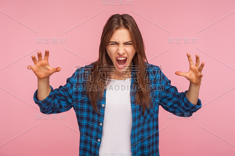 愤怒的女孩的肖像穿着格子衬衫与愤怒疯狂的鬼脸举起手和呼喊的仇恨