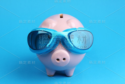 蓝色背景上带蓝色泳镜的粉色储蓄罐