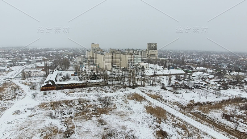 谷物在冬季终了。农村地区被雪覆盖的粮食升降机。干燥和储存谷物的建筑物。