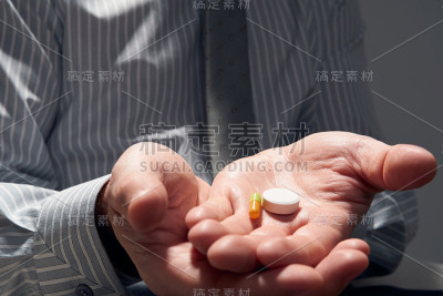 商人带着一粒药丸，双手近距离观察——概念上的困难、抑郁、问题、健康和压力、现代商业风险