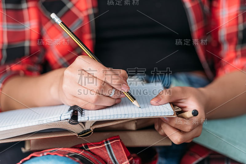 学生拿着书，用铅笔在笔记本上写字的镜头