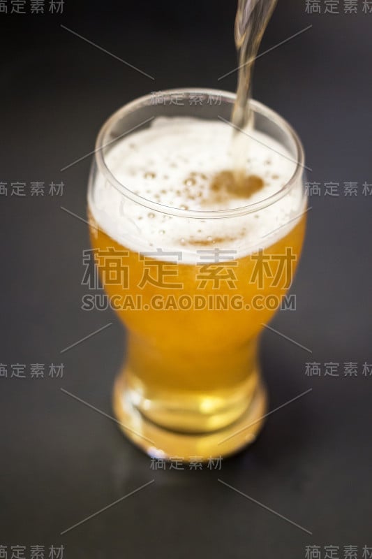 将啤酒倒进一个黑色背景孤立的高脚杯