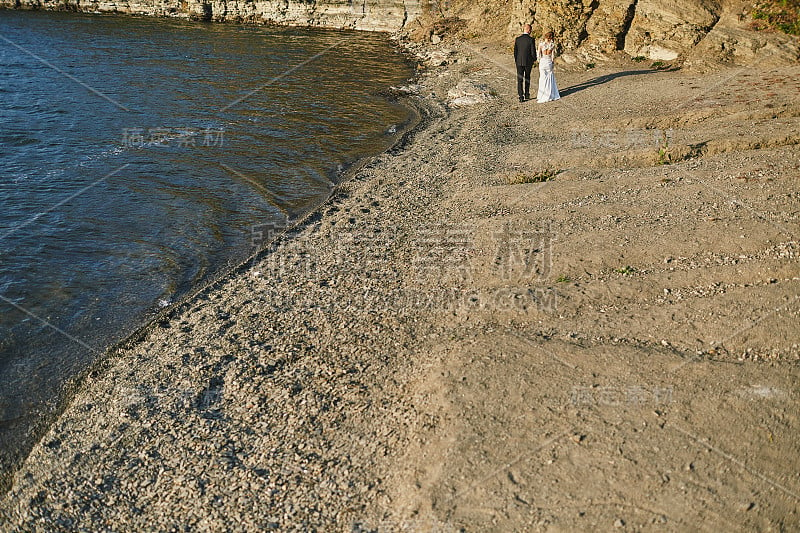 情侣们穿着婚纱靠近大海和群山