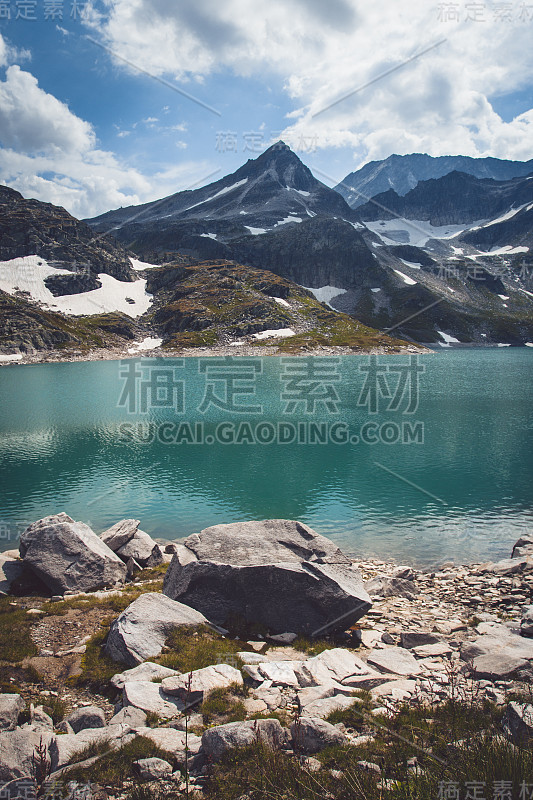 美丽的奥地利高山湖泊威斯湖，周围有高高的，小雪山，草地上有许多花。