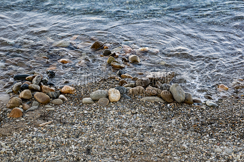 巨大而光滑的石头在咸海水的海岸波浪中。黑海海岸泛着泡沫，咆哮着