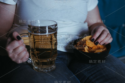孤独的女人看电视吃垃圾食品喝啤酒