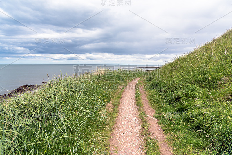 在阴沉的春天天空下的海岸小径