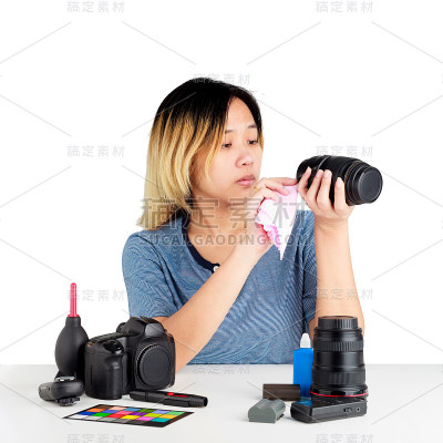 一名亚洲妇女正在用桌布和桌子上的摄影器材清洁照相机。对象隔离在白色背景与剪切路径和复制空间。