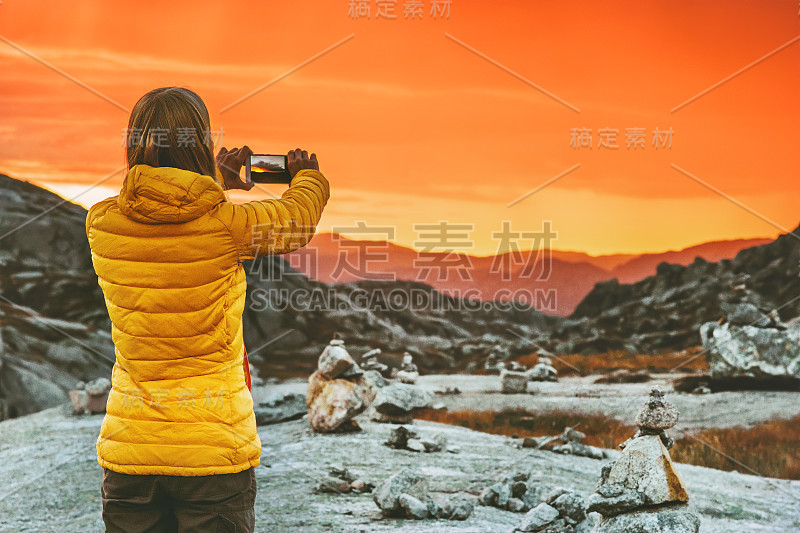 女性博主用智能手机拍摄日落山景观旅行生活概念冒险度假在挪威户外现代科技