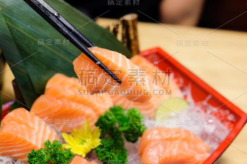 三文鱼生鱼片，用筷子夹起一片三文鱼片，健康饮食