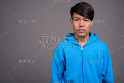 在灰色背景下穿着蓝色夹克的年轻亚洲男孩的工作室拍摄