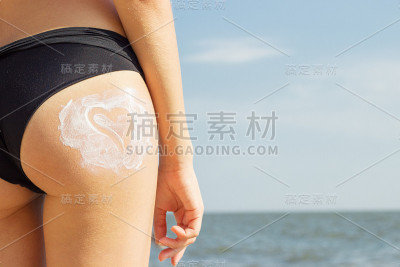 有魅力的女性，健康的皮肤涂抹防晒霜在她的臀部心脏的形式