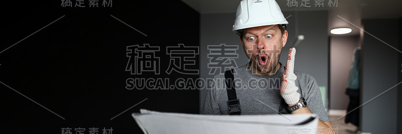 年轻的修理工站在空荡荡的公寓里，看着施工图，感到震惊