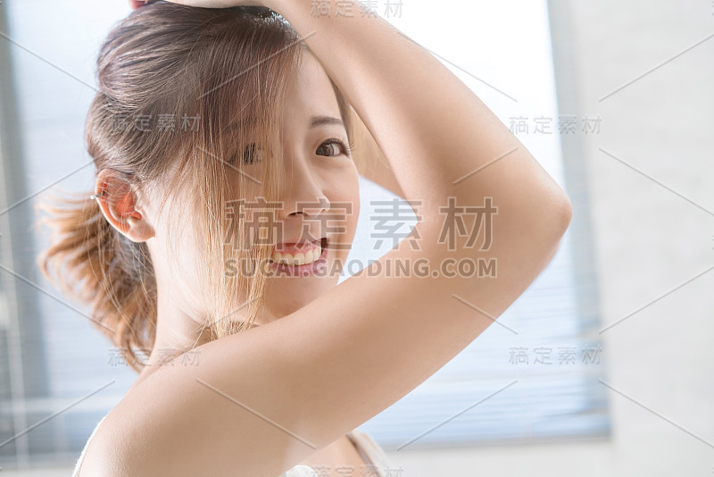 近距离的微笑女人化妆刷近脸和看镜子。亚洲美女