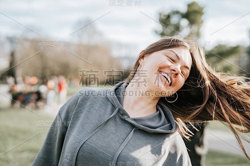 近距离的肖像有吸引力的40岁的女人享受生活玩她的头发和微笑与牙齿的微笑户外。不化妆，自然美。休息一下