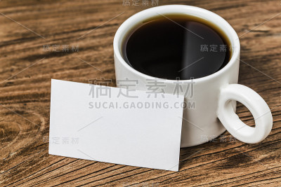 木桌上放着空白的名片和一杯咖啡。企业文具品牌模拟。