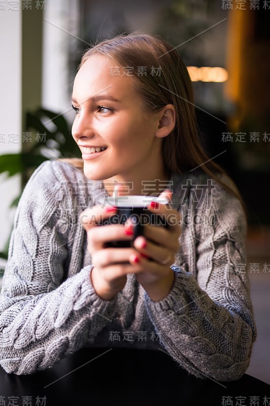 美丽微笑的女人在咖啡馆喝咖啡。一个成熟女人在自助餐厅喝着热卡布奇诺看着镜头的肖像。喝咖啡的漂亮女人。