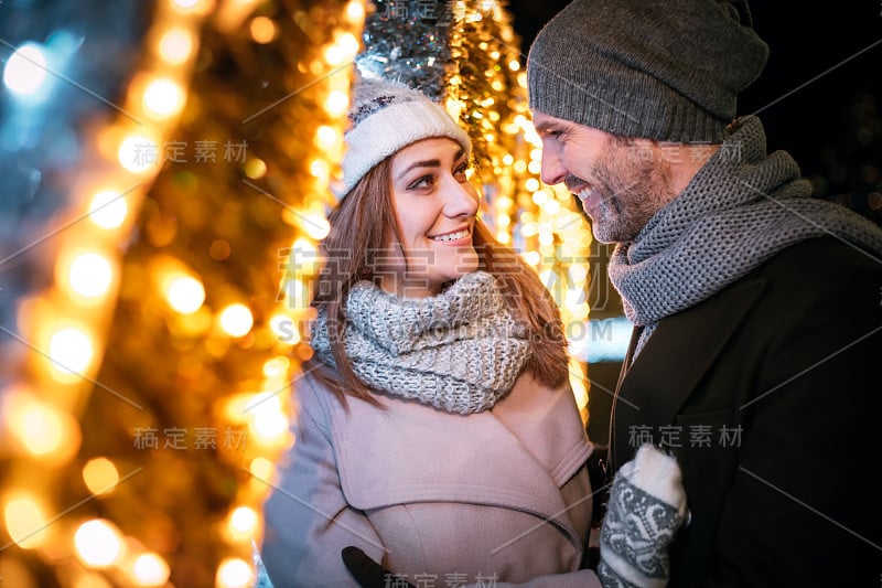 在圣诞街道的装饰中相爱的夫妇拥抱