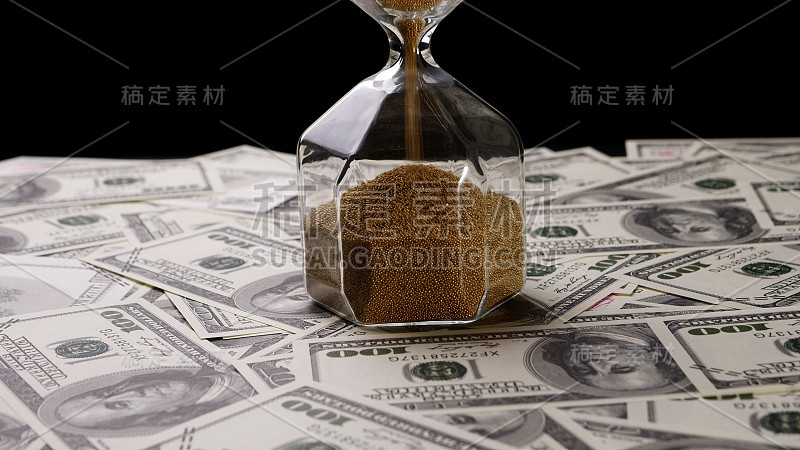 棕色的沙子倒入透明的沙漏在钞票上