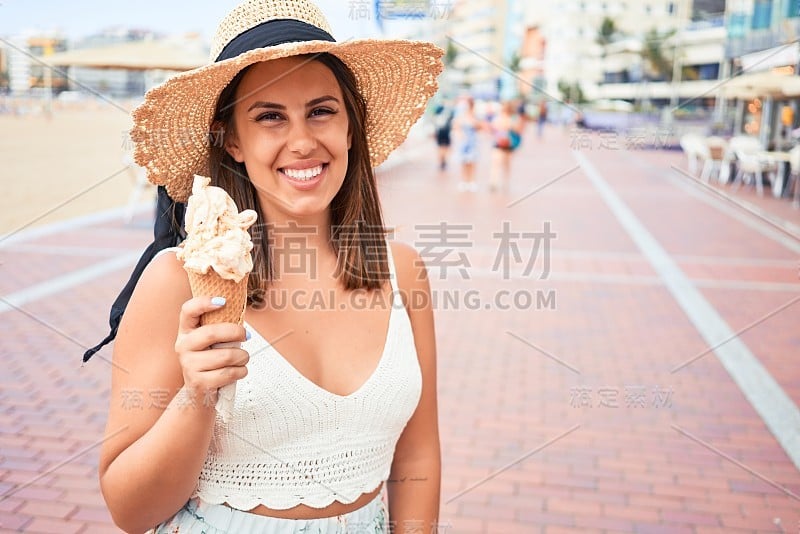 年轻漂亮的女人在一个阳光明媚的夏日假日在海滩上吃冰淇淋